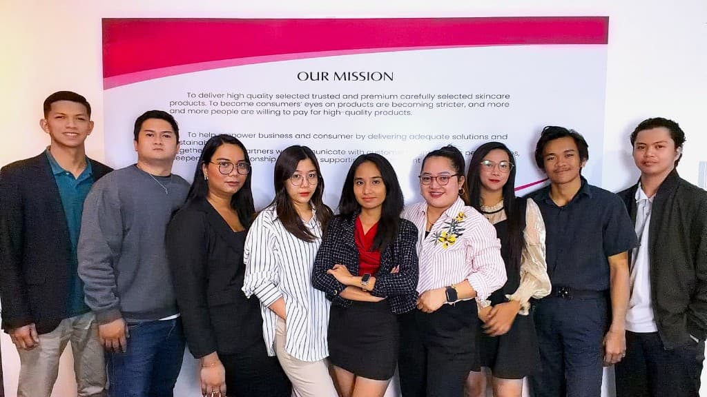 SeiraNow team members together in front of the office wall displaying our mission statement.